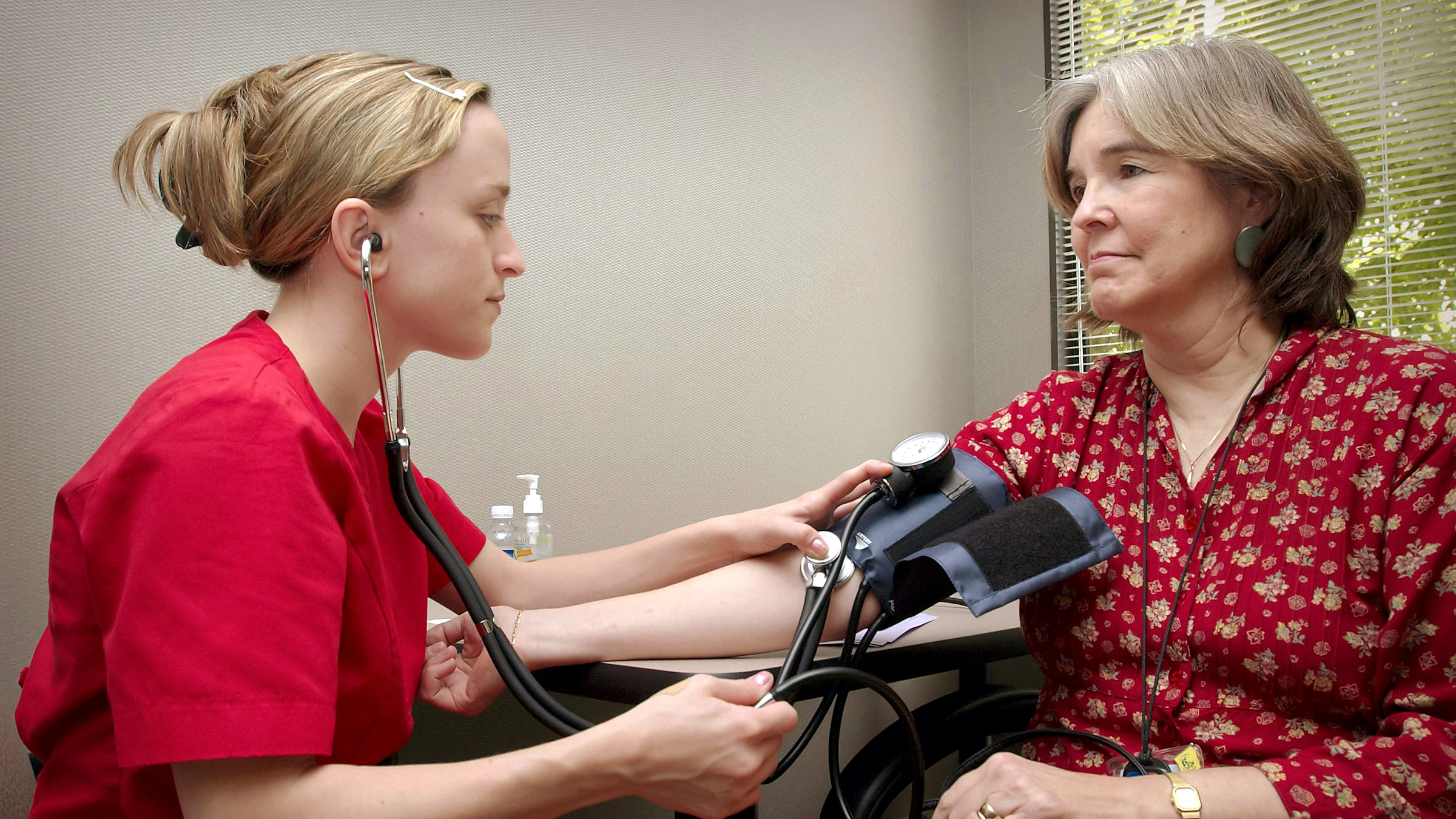 A nurse taking an older woman's blood pressure at a routine check up